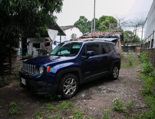 Blue Jeep SUV parked on a dirt road in a residential area in El Salvador, offering reliable travel and transport services for Surf City visitors.