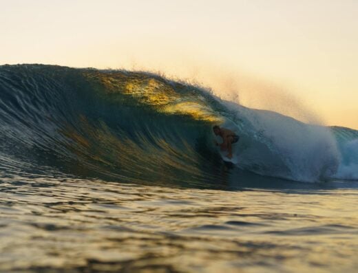 Surfer riding a wave at sunset in Siargao, Philippines, capturing the vibrant surf scene and tropical beauty. Perfect for surf tourism and adventure travel enthusiasts.