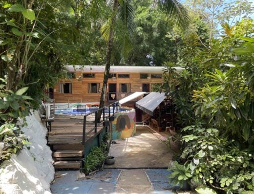 Shared bathroom area at a tropical hostel surrounded by lush greenery, wooden structures, and outdoor amenities, ideal for travelers seeking a natural and relaxing stay.