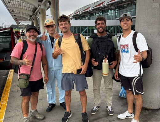 Group of five diverse travelers with backpacks and water bottles at airport pickup area, ready for transportation with Pancho Taxi & Rental Car services.