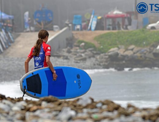 Young girl holding a surfboard during surf lessons at Lima's beach, promoting top surf training in Peru.