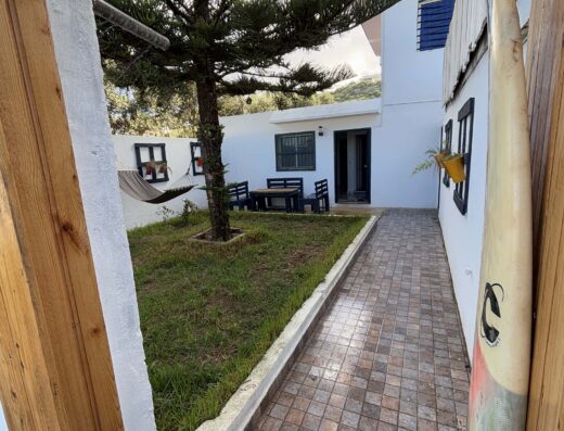 View of the outdoor area of Oualidia surf house with a garden, pathway, and surfboard, perfect for surfing enthusiasts seeking a relaxing seaside stay.