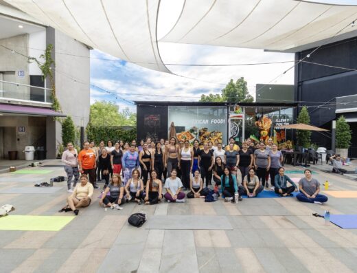 Outdoor yoga class with diverse participants practicing on mats under a modern canopy.