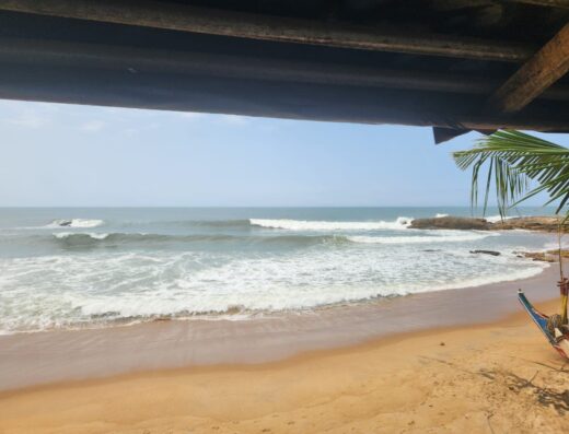 Under a wooden shelter overlooking the ocean in Assouindé, Côte d'Ivoire, a tranquil private room offers a peaceful retreat with direct beach access and scenic sea views.