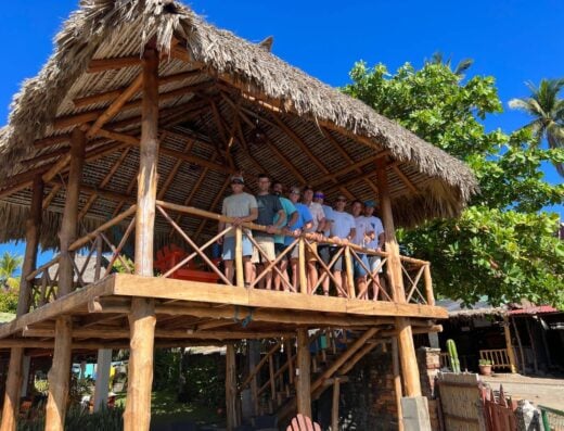 Beachfront treehouse with a group of people enjoying the view at K59 Surf Resort, perfect for tropical vacations and surfing adventures.