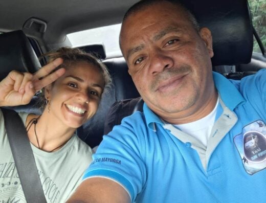 A smiling young woman and a taxi driver taking a selfie inside a vehicle at Popoyo, showcasing a fun surfing trip experience.