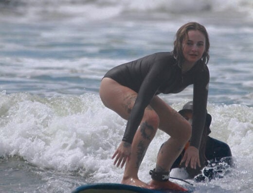Surfing with a female surfer riding a wave in Jacó, Costa Rica, showcasing local surf culture and ocean adventure.