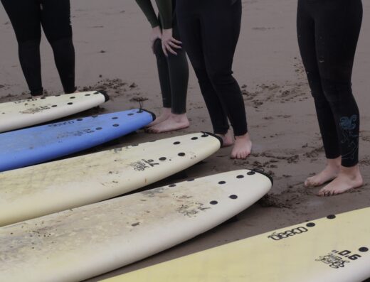 Surfing and yoga session at El Marjana, a female-led surf and lifestyle retreat in Morocco, featuring participants preparing for a day of surfing on the sandy beach.