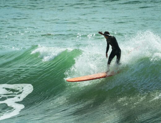 Experienced surf instructor riding a wave on a surfboard, demonstrating skills and confidence in the ocean. Perfect for surf lessons and guiding beginners.