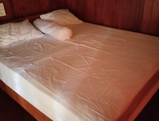 Comfortable bed in a rustic wooden surf homestay at Katiet, perfect for surfers seeking a relaxing stay near the barrels.