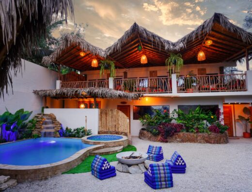 Luxurious beachfront villa featuring a private pool, thatched roof terraces, and a spacious balcony overlooking the ocean, perfect for relaxing and enjoying the surf.