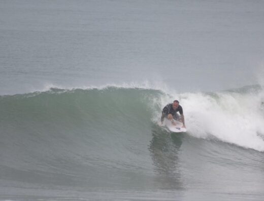 A surfer riding a wave during a surf session at a popular beach.