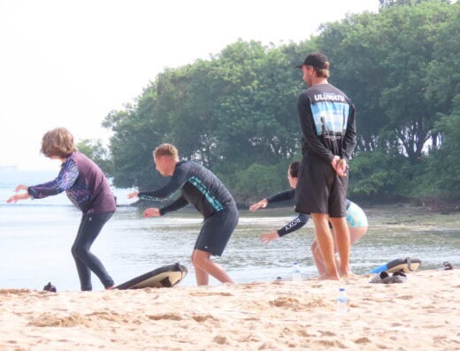 Surf lesson for beginners at the beach, teaching kids and adults how to balance and ride waves safely.